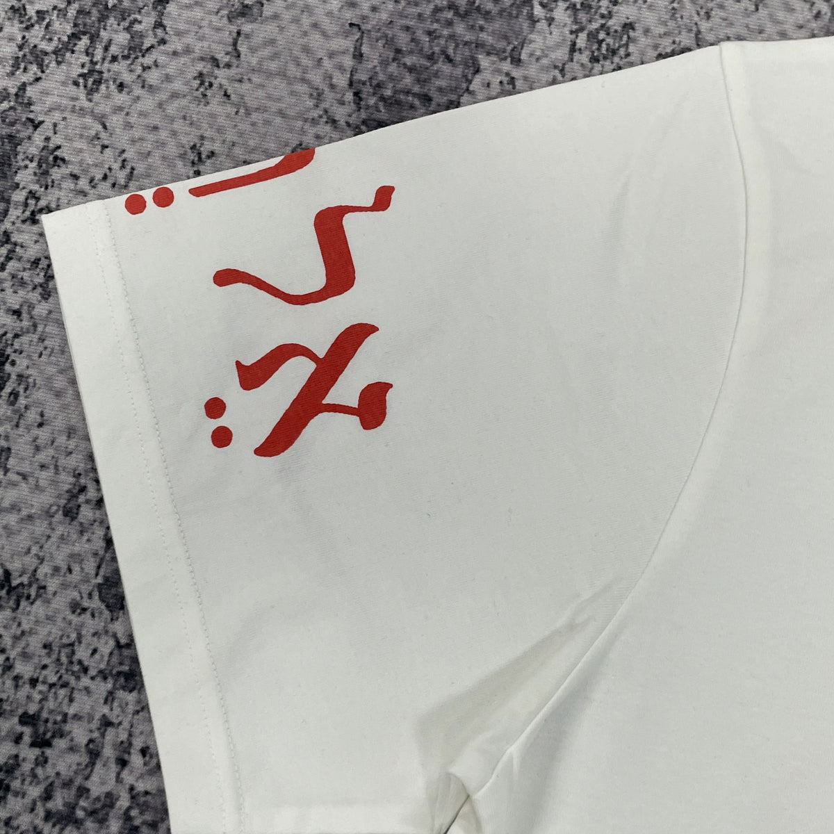 Close-up of red graphic on one white T-shirt sleeve